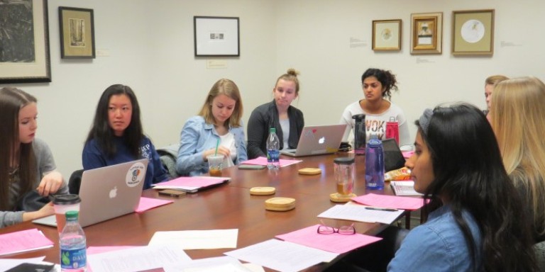 An executive board meeting in progress with students sitting around a large table.